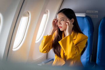 Young asian chinese airplane passenger woman experiencing discomfort, Airplane headache. Worried...