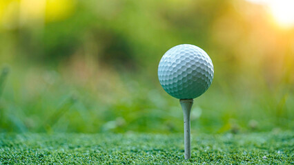 Golf ball on tee at green lawn in a beautiful golf course with morning sunshine.