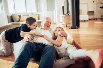 Playful grandfather having fun with his grandchildren in the living room