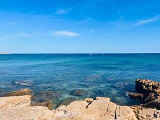 Fototapeta na wymiar Transparent blue sea water, ocean bay, rocky coast, blue sky