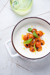 Tirokafteri or greek feta dip sauce with tomatoes in a serving pan, vertical shot on a white...