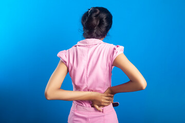 Portrait of an Indian girl suffering from waist inflammation against blue background