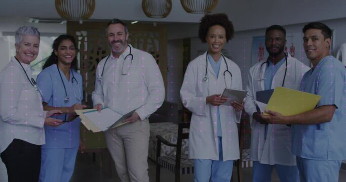 Animation of heart rate monitor over team of diverse doctors and health workers smiling at hospital