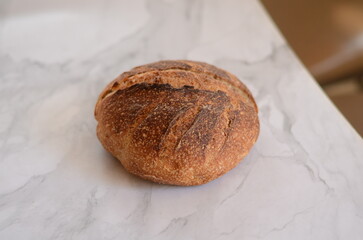 Freshly baked pretty loaf of homemade delicious sourdough bread sliced open on table/counter 