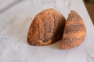 Freshly baked pretty loaf of homemade delicious sourdough bread sliced open on table/counter 