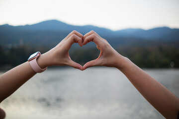 young woman and her friend raised their hands together to form heart shape to show their friendship love and kindness with their belief and power of faith in their friendship. concept of friendship - obrazy, fototapety, plakaty
