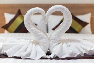 White towels folded into the shape of a pair of swans to symbolize love and fidelity are placed on...