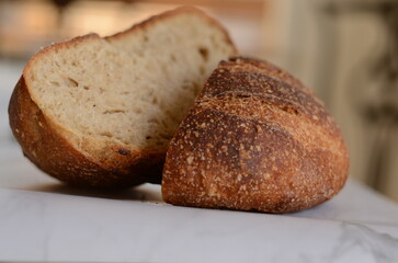 Freshly baked pretty loaf of homemade delicious sourdough bread sliced open on table/counter 