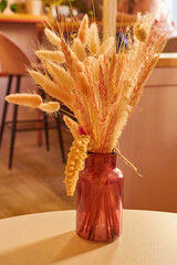 Photo a pink glass vase with dried flowers
