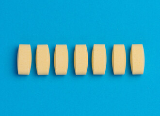 Yellow oval tablets on a blue background, top view