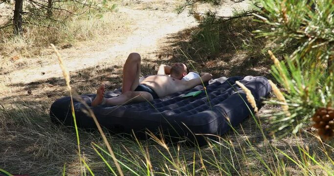 A Man Sleeping on an Inflatable Mattress in the Sunny Forest during His Summer Vacation