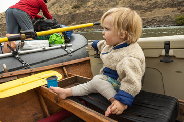 A young boy sits in a drift boat during a family rafting trip down the Deschutes River in Oregon.