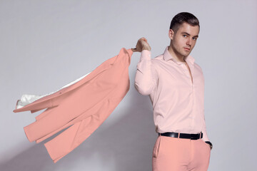 A man in a pink suit and a fashionable pink shirt on a gray background. A man in a Barbie outfit.