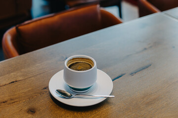 Cup of black coffee on a wooden table in a cafe.