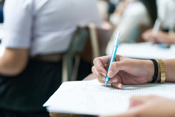 Selective focus high school or university students concentrate writing on paper answer sheet for...