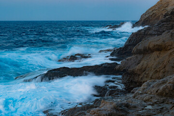 Long exposure photography of waves in motion hitting the rocks of the Ikarian coast