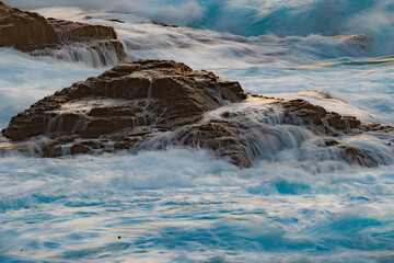 Long exposure photography of waves in motion hitting the rocks of the Ikarian coast