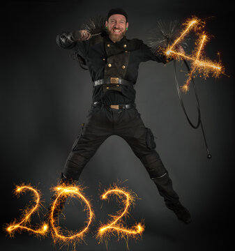 Symbolbild für Jahreswechsel 2024, Sternspritzer, Schornsteinfeger in Arbeitskleidung, mit Kehrgeräten springt und freut sich auf das Neue Jahr 2024