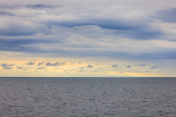 Fototapeta premium Distant horizon between cloud layer and calm seas at sunrise