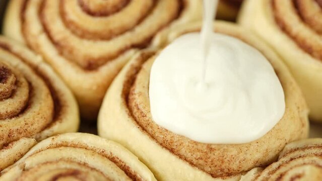 Fresh baked cinnamon bun.  Pouring cream on cinnamon rolls