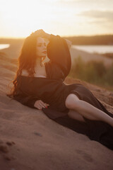 Beautiful woman relaxing on the beach at sunset wearing a black dress and closed eyes. Concept for wellness, travel, relaxation or meditation.