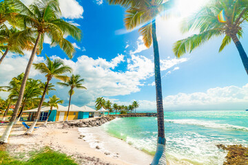 Sun shining over beautiful Bas du Fort beach in Guadeloupe - obrazy, fototapety, plakaty