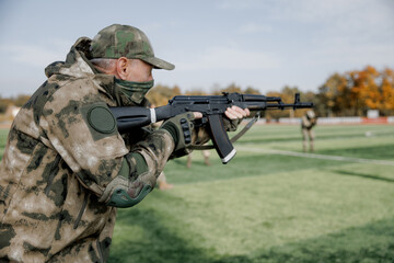 Fototapeta premium Soldiers in formation. Soldiers with a machine gun in military uniform. Special forces with weapons take part in a military maneuver. War, army, equipment and the concept of people. Camouflage. Traini