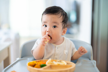 離乳食後期でをつかみ食べをしてご機嫌な生後9か月の赤ちゃん