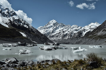 The majestic Mount Cook in New Zealand, a glacial lake, a bright blue sky, snow and icebergs floating in the water - a spectacular and frosty scenery.