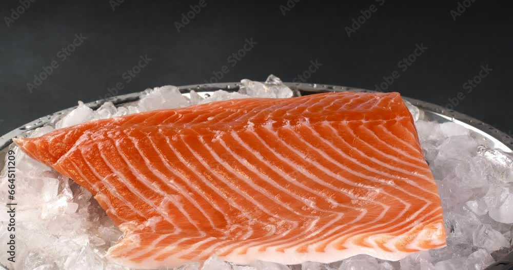 Wall mural salmon on a tray with ice on a dark background. close-up footage on the rotating table.