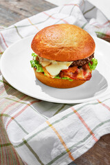 Craft beef burger on plate isolated on wooden background with towel