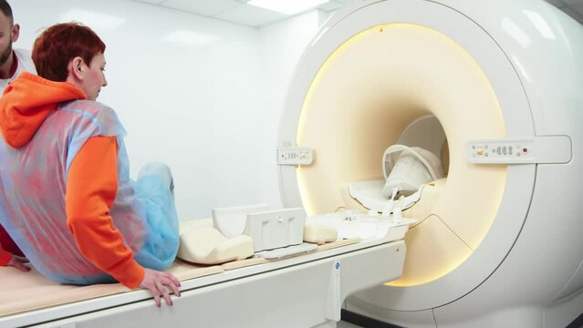 A doctor performs an MRI on a patient in the clinic. The girl lies in an MRI machine. Magnetic resonance imaging in the study of the knee joint. Modern technologies in medicine.