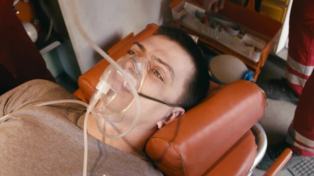 Patient, paramedic and blood pressure with oxygen mask in ambulance for emergency, trauma or medical care. First aid, human and anesthesia for medical health.