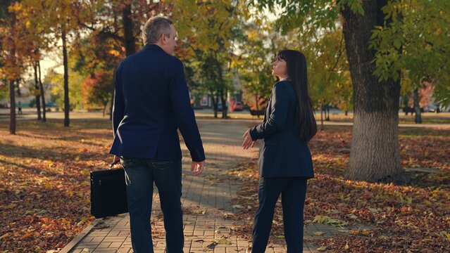 Businessmen In Suits Talking, Walking Through, City Autumn Park. Politicians. Business People Man Woman Communicate, Discuss Business, Team Work. Business Woman Partners Successful Cooperation, Nature