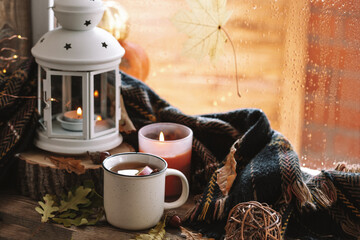  Mug of hot tea with apple and cinnamon on the autumn window. Autumn and fall cozy postcard