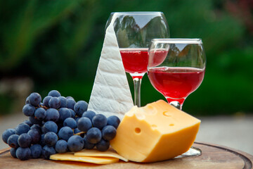 Composition with a glass of red wine, grapes and cheese. Red natural wine, cheese and a bunch of...