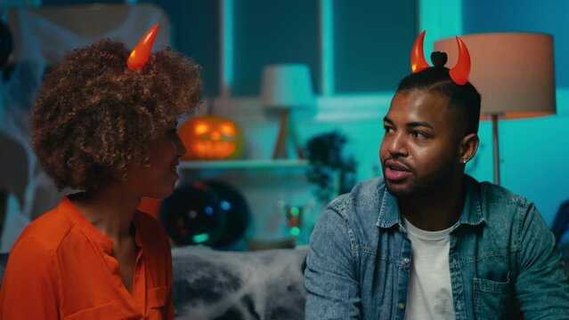 Happy African American woman and man with devil horns celebrating Halloween, fun