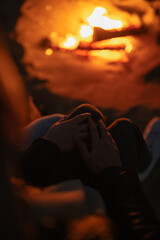 Unrecognizable couple holding hands sitting near campfire