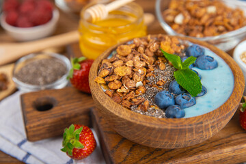 Bowl of granola with yogurt and fresh berries on a texture table. Yogurt berries, acai bowl, spirulina bowl. Healthy food, balanced breakfast. Strawberries, blueberries, kiwi, peach, almonds and chia.