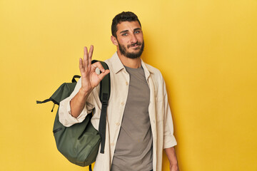 Young Hispanic man with travel backpack cheerful and confident showing ok gesture.