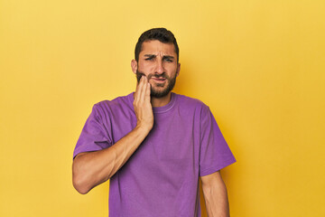 Young Hispanic man on yellow background having a strong teeth pain, molar ache.