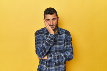 Young Hispanic man on yellow background who is bored, fatigued and need a relax day.