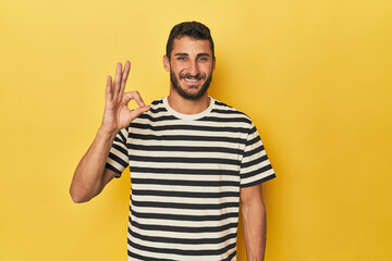 Young Hispanic man on yellow background cheerful and confident showing ok gesture.