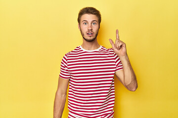 Young Caucasian man on a yellow studio background having an idea, inspiration concept.