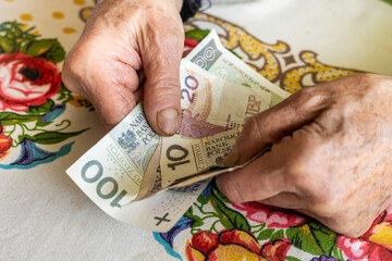 Polish old woman pensioner clutches money in her hands, small amount, Concept, Difficult financial situation of elderly people in Poland, Rising fees and food prices, close up - obrazy, fototapety, plakaty