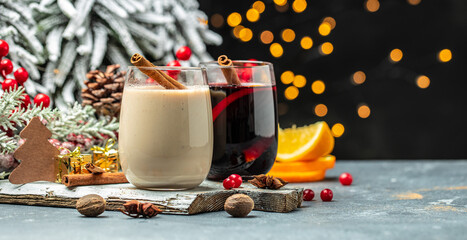 Cozy atmosphere with glasses of mulled wine and Eggnog, Christmas winter alcohol drinks decorated by christmas lights