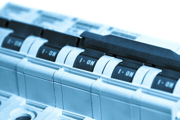 Mains electricity circuit breakers isolated on a white background. With blue colour toning