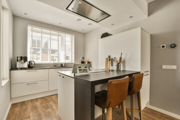 a kitchen and dining area in a modern apartment with wood flooring, white cupboards and wooden bar stools