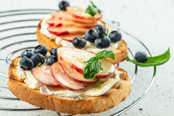 Peach bruschetta with ricotta cheese and blueberries on a wooden board. Food recipe background. Close up