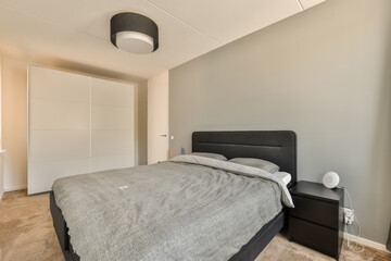 a bedroom with a bed, nightstand and closets in the room is light gray walls there are two lamps on either sides